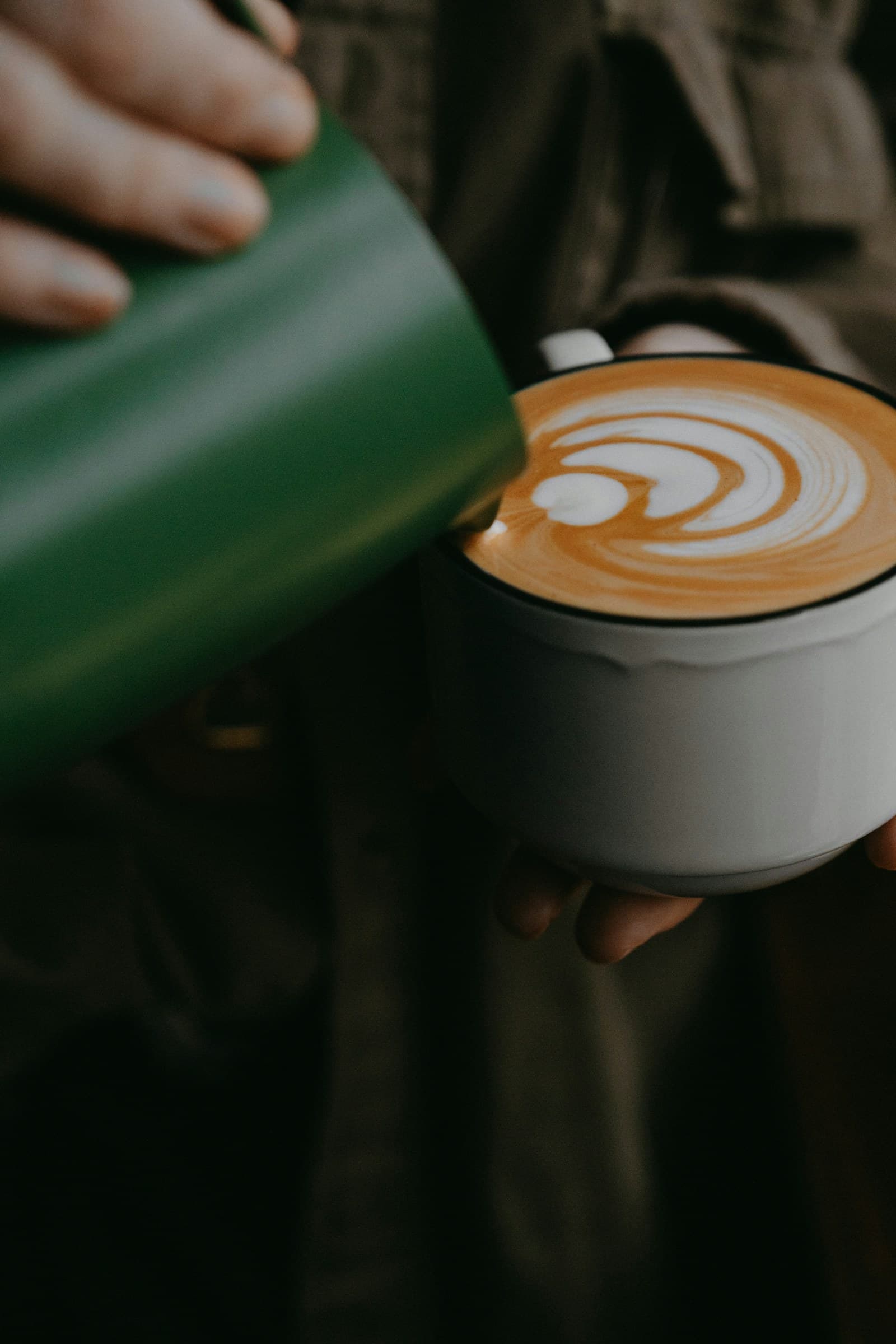A barista pouring latte art into a cup of coffee